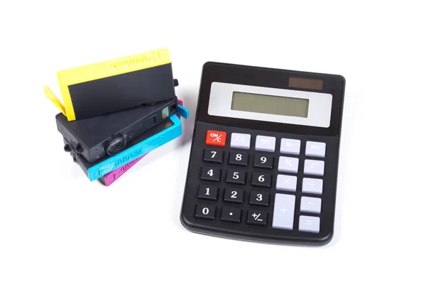 Stack of color printer cartridges and calculator — Stock Photo, Image