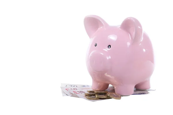 Pink piggy bank on a pile of sterling cash — Stock Photo, Image