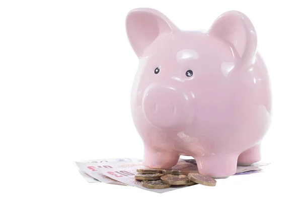 Piggy bank standing on a pile of UK money — Stock Photo, Image