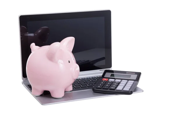 Calculadora e banco porquinho em um laptop caneta — Fotografia de Stock