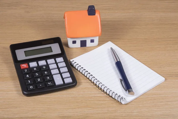Modelo casa, calculadora e notebook com caneta — Fotografia de Stock