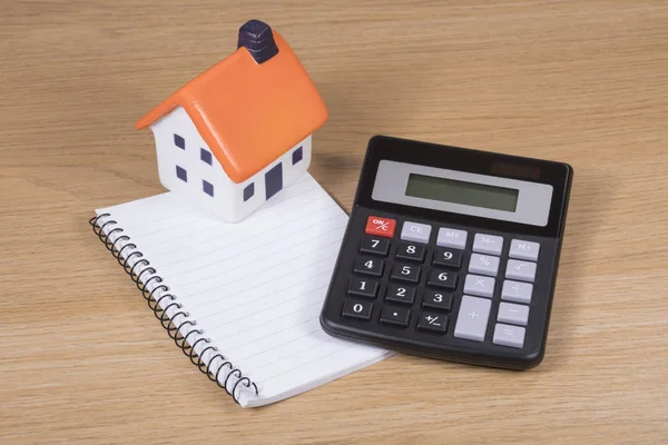 Pequena casa modelo com calculadora e notebook — Fotografia de Stock