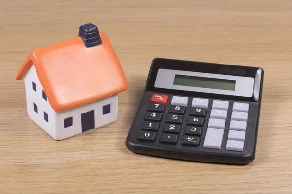 Calcolatrice con piccolo modello di giocattolo di una casa — Foto Stock