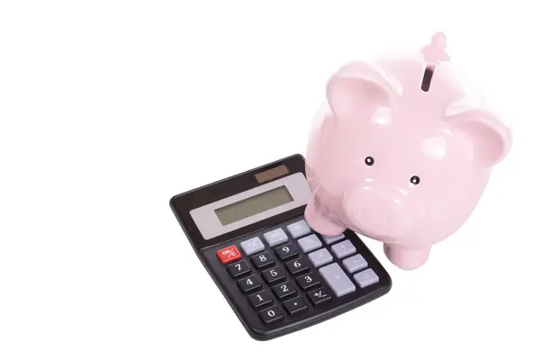 Banco porquinho com um pé em uma calculadora — Fotografia de Stock