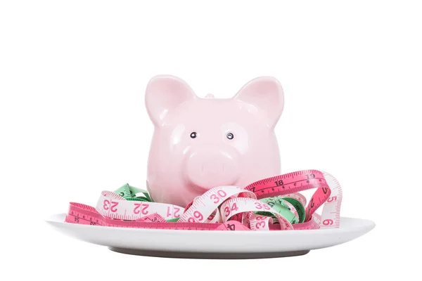 Pink piggy bank with tape measures on a plate — Stock Photo, Image