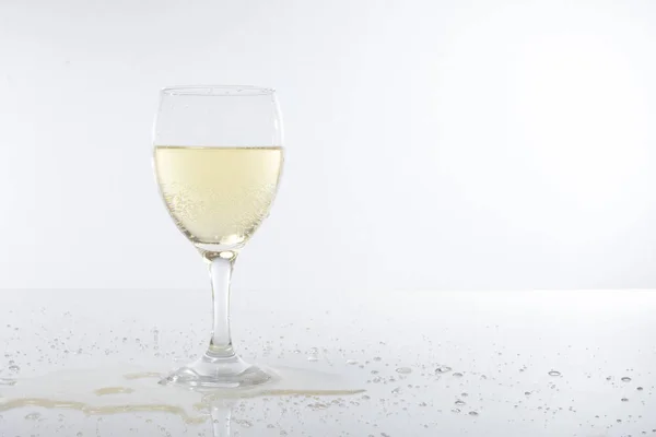 Наполненный бокал вина и пролитое шампанское на бар — стоковое фото