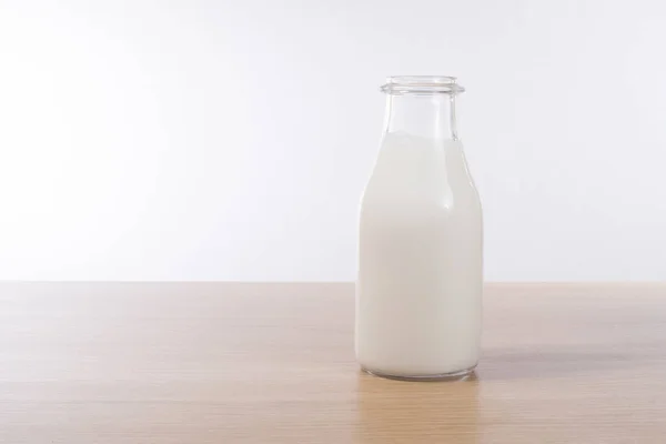 Glasflasche mit frischer Milch auf Tischplatte — Stockfoto
