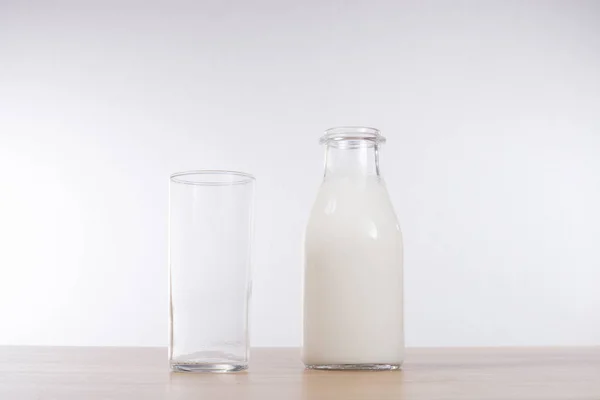 Grand verre à côté d'une bouteille de lait — Photo