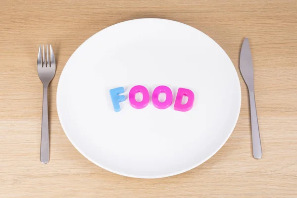 Een mes, een vork en een leeg bord met het woord voedsel — Stockfoto
