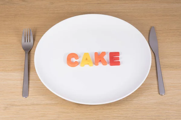 A knife, fork and empty plate with the word cake — Stock Photo, Image