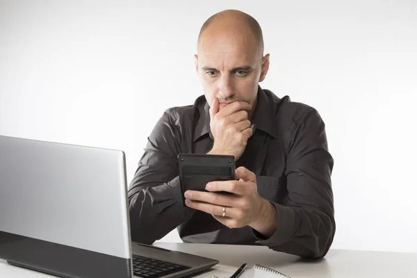 Worried man staring at a handheld calculator — Stock Photo, Image