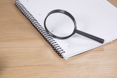 Büyüteç masanın üzerinde yatan boş not defteri üzerinde