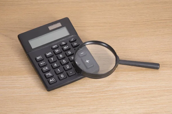 Calculadora com lupa na mesa — Fotografia de Stock