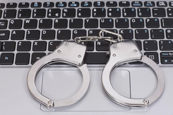 Pair of toy handcuffs on a computer keyboard