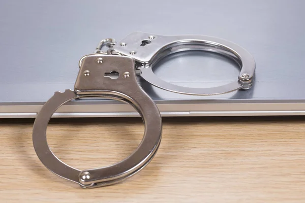 Close up of handcuffs on a closed laptop — Stock Photo, Image