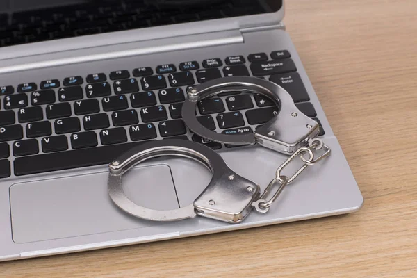 Open laptop with locked handcuffs on the keyboard