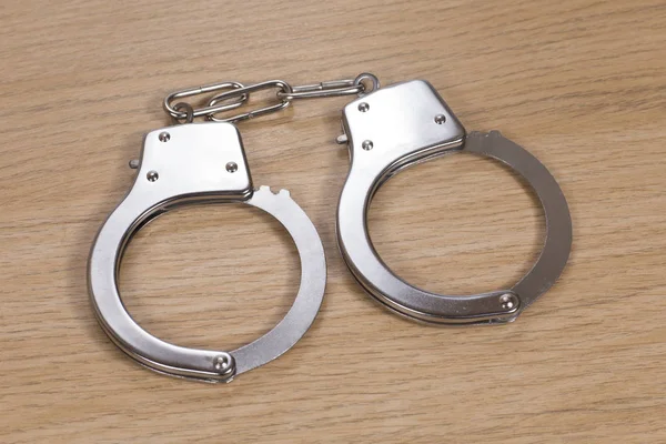 Pair of close handcuffs on wood — Stock Photo, Image