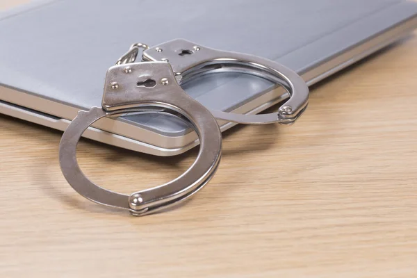 Handcuffs on a closed laptop computer — Stock Photo, Image