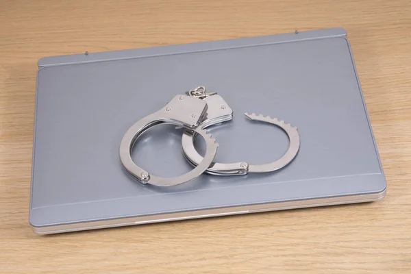 Handcuffs lying on laptop — Stock Photo, Image