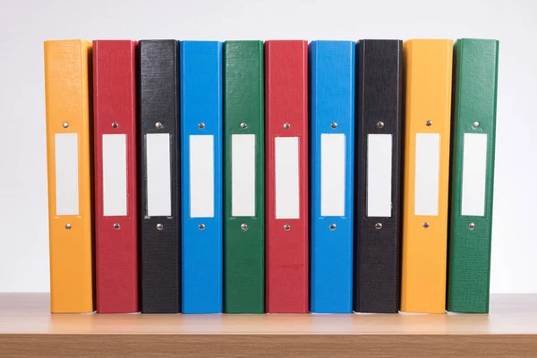 Rij van gekleurde office documentmappen op plank — Stockfoto
