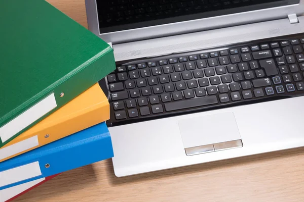 Neat office desk with laptop and stacked folders