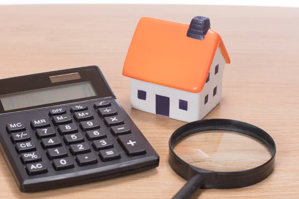 Model of house among magnifier with calculator — Stock Photo, Image