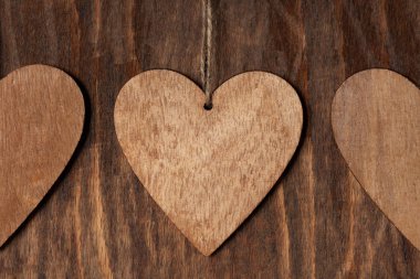 Ahşap arka plan üzerinde ip ile üç ahşap kalp