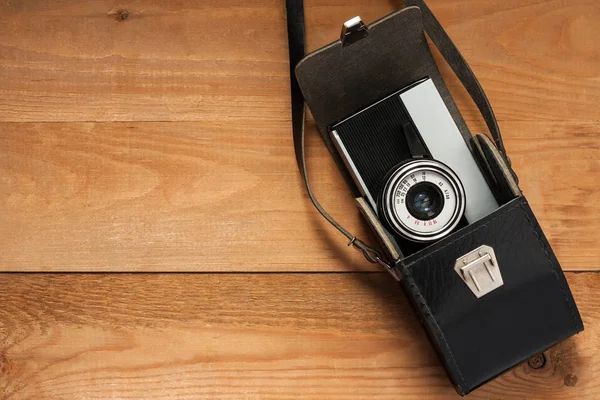 Câmera retro velha vintage no saco de couro preto na placa de madeira Co — Fotografia de Stock