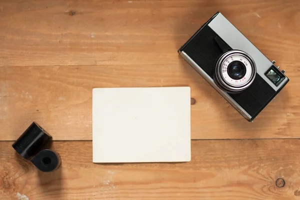 Vieil appareil photo rétro, film et liste blanche sur panneau brun en bois . — Photo