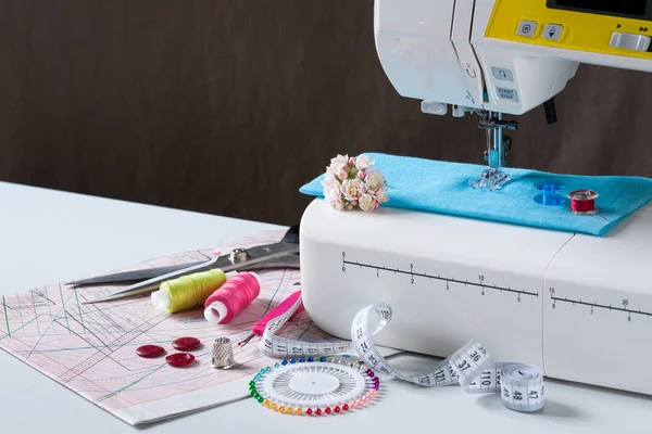 Швейная машина с различными аксессуарами на белом столе . — стоковое фото
