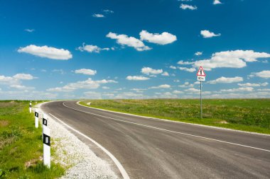 Asfalt yol ile mavi gökyüzü ve beyaz bulutlar.