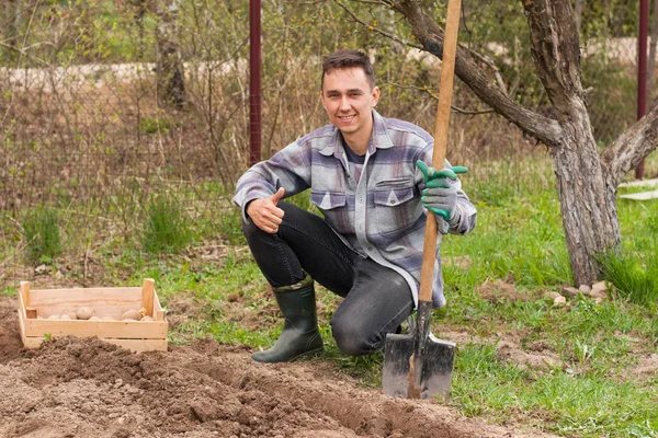 Bahar günü erkek bahçıvan beklemede kürek bahçe içinde.