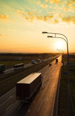 Sunrise altında uzak yolda taşıma araçları gidin.