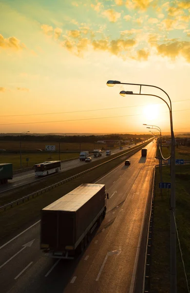 Sunrise altında uzak yolda taşıma araçları gidin.