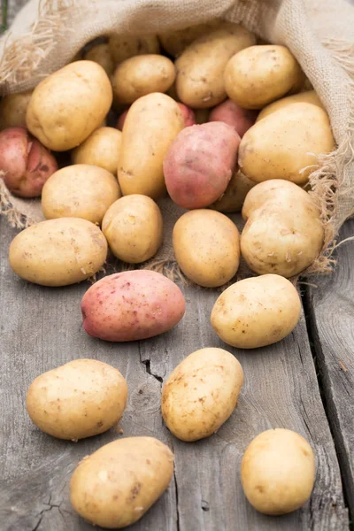 Aardappelen met Sackcloth op houten tafel. — Stockfoto