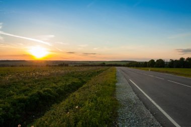 Asfalt yol yolda günbatımı güneş üzerinde tarım.