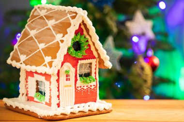 Noel Zencefilli Kurabiye Evi, Noel ağacının arka planında yanan çelenklerle birlikte ahşap masada sergilendi.