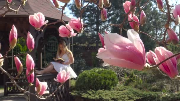 Lieblingslektüre im blühenden Magnoliengarten ist ein wahrer Genuss. — Stockvideo