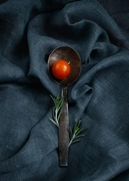 Stylish table appointments. Silver spoon with rosemary and cherry tomato.