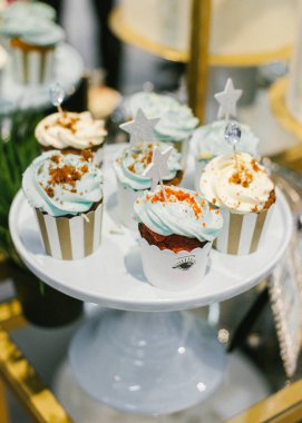 Beyaz seramik Kaide üzerine krem peynir ile şık düğün cupcakes kümesi.