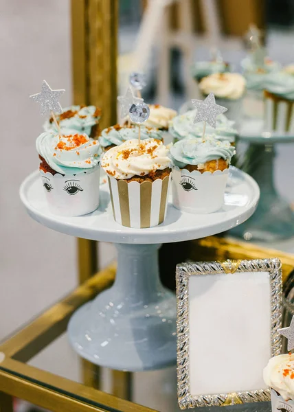 Set of stylish wedding cupcakes with cream cheese on white ceramic pedestal.