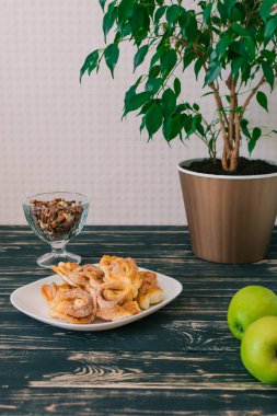 Tarçınlı ekmekler siyah ve beyaz tabakta. Elma parçacıkları beyaz tabak ve taze yeşil elma. Kolay ve Temel tatlı menüsü.
