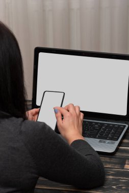 Kız bir cep telefonu kullanıyor. Ev konforunda dizüstü bilgisayarda çalışıyor, evde çalışıyor, siyah not ve kalem, online, serbest.