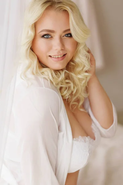 blonde girl plus size model in white lingerie portrait Bali morning bride  color smiles coquettishly sitting in a light interior big Breasts Stock  Photo