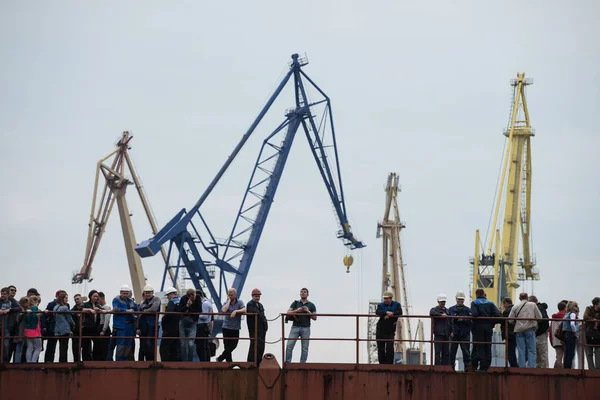 Dělníci v loděnicích na přístaviště na pozadí jeřábů. — Stock fotografie