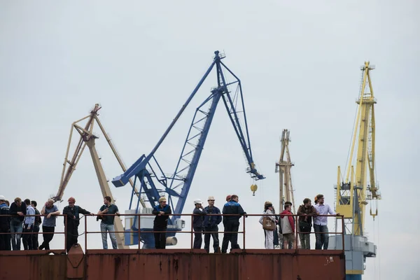 Trabajadores de astilleros en el muelle sobre un fondo de grúas . — Foto de Stock