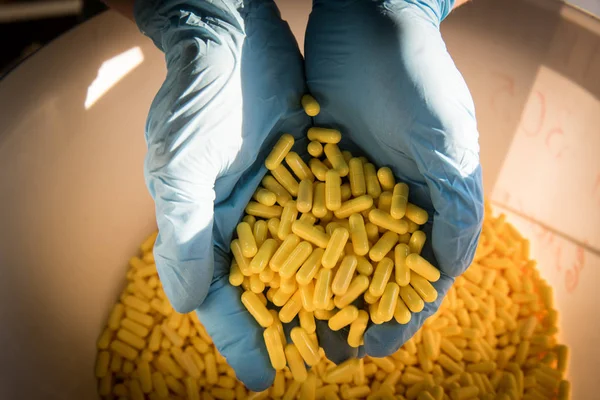 Handful of yellow medical capsules in the hands