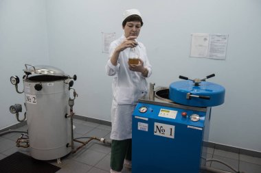 Saint-Petersburg, Rusya - 6 Aralık 2016: Kimyager kozmetik ve beslenme takviyeleri üretimi için bir kimya fabrikasında endüstriyel buhar jeneratörleri kullanan bir kozmetik ürünü test ediyor