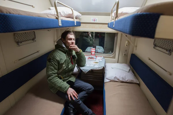 Een passagier van een jonge man zitten in een trein compartiment — Stockfoto