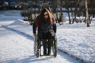 Saint-Petersburg, Rusya - 27 Şubat 2017: Bir şehir parkında tekerlekli sandalyede yürüyen güzel bir kız.